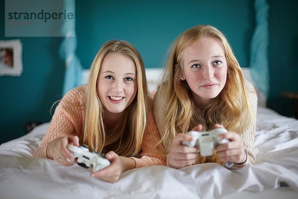 Zwei Teenager-Mädchen beim Computerspiel im Schlafzimmer