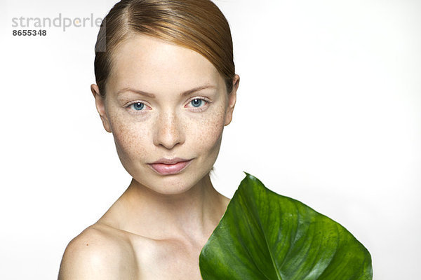 Junge Frau mit tropischem Pflanzenblatt  Portrait