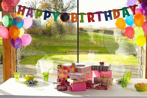 Tisch gedeckt mit Geburtstagsgeschenken und Ballons