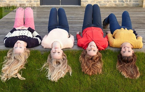 Vier Teenager-Mädchen liegen auf der Terrasse und schauen zurück.