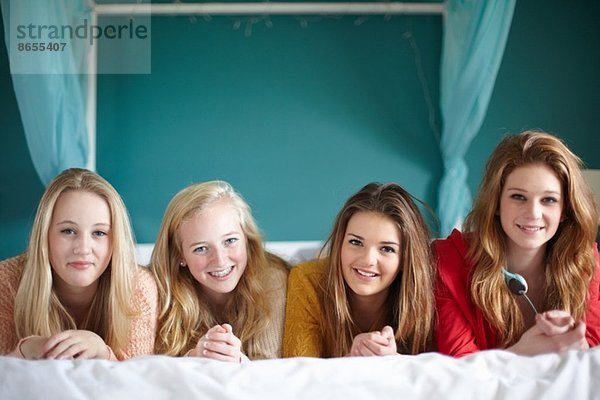 Porträt von vier Teenagern auf dem Bett liegend