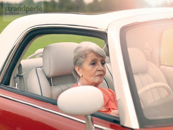 Seniorin fährt rotes Cabriolet