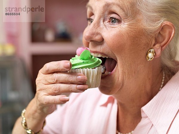 Seniorin genießt Muffin im Cafe
