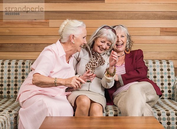 Seniorinnen  die auf dem Sofa lachen.
