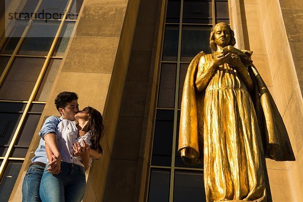 Junges Paar  das sich einen Kuss neben der Statue teilt  Paris  Frankreich