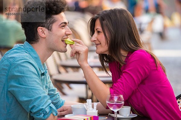 Junges Paar isst Makrone im Straßencafé  Paris  Frankreich