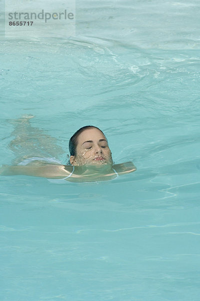 Junge Frau schwimmt im Schwimmbad  Augen geschlossen