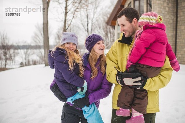 Mutter und Vater mit Töchtern im Schnee