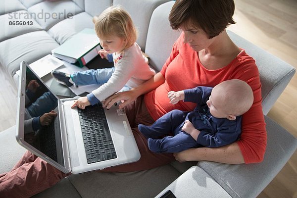 Mutter  Junge und Kleinkind mit Laptop auf dem Sofa