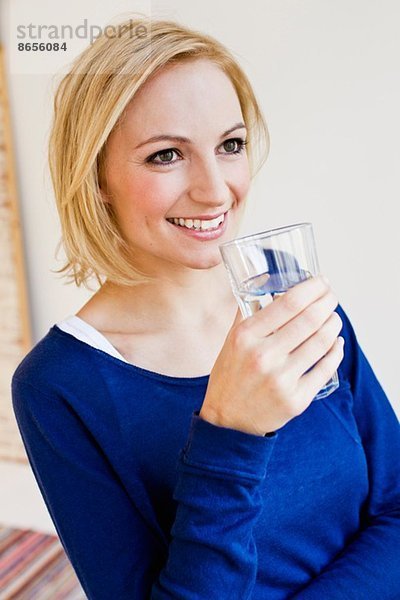 Atelierporträt einer jungen Frau mit Wasserglas