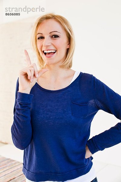 Studio-Porträt einer jungen Frau  die mit dem Finger zeigt