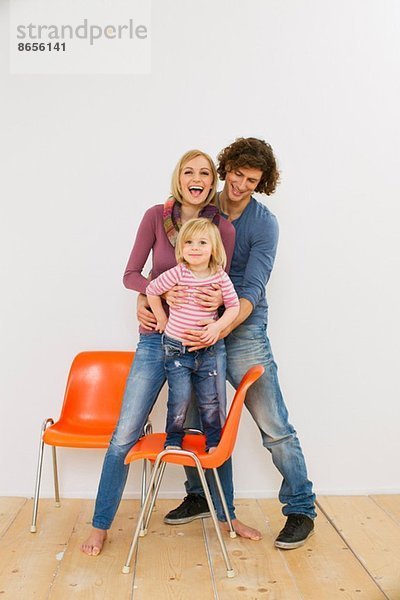 Studioaufnahme eines Paares mit einer kleinen Tochter auf einem Stuhl