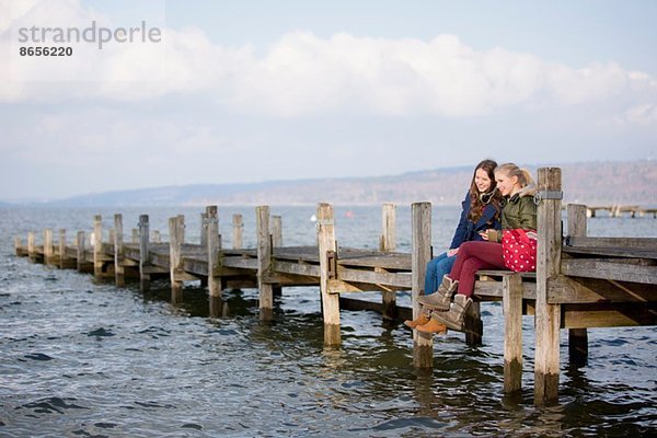 Teenager-Mädchen sitzen auf dem Steg