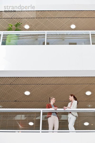 Zwei weibliche Arbeitskolleginnen machen Pause auf dem Bürobalkon