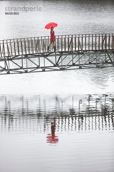 Junge Frau in roter Fußgängerbrücke im Regen