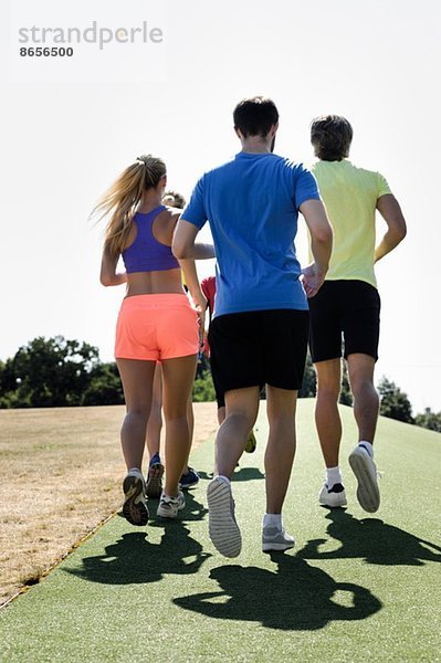 Reife Trainerin beim Laufen mit Erwachsenengruppe im Park