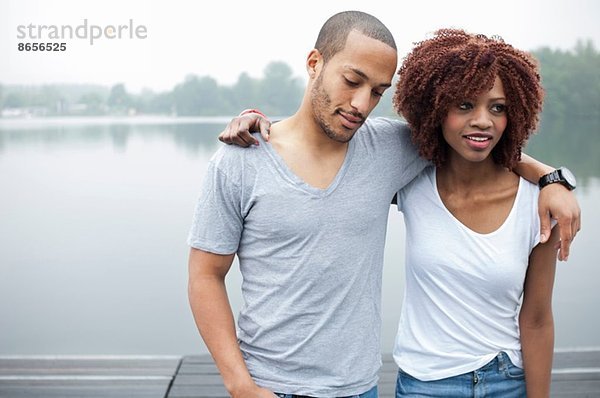 Porträt eines jungen Paares am See mit umlaufenden Armen