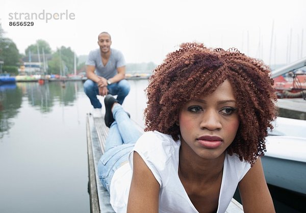 Porträt einer traurig aussehenden jungen Frau mit Mann im Hintergrund