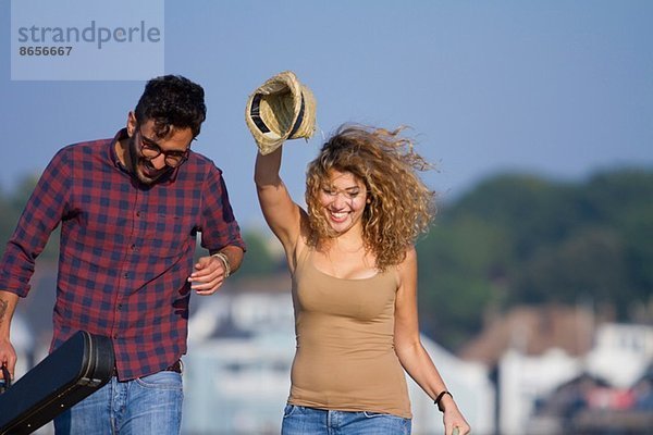 Junges lachendes Paar  Frau mit Hut in der Hand