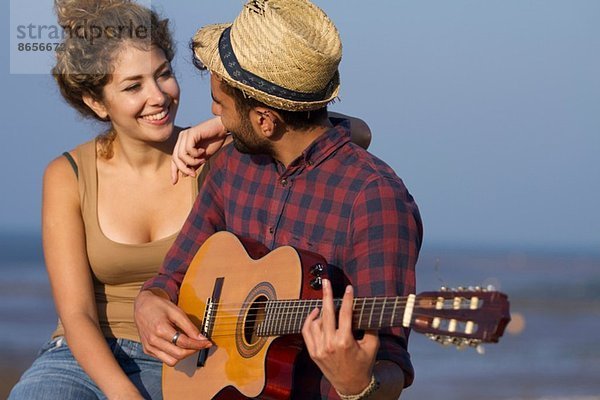 Junges Paar  Mann spielt Gitarre