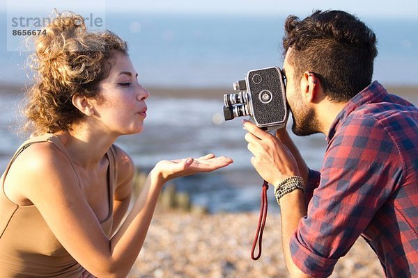 Junger Mann filmt Frau mit Vintage-Kamera