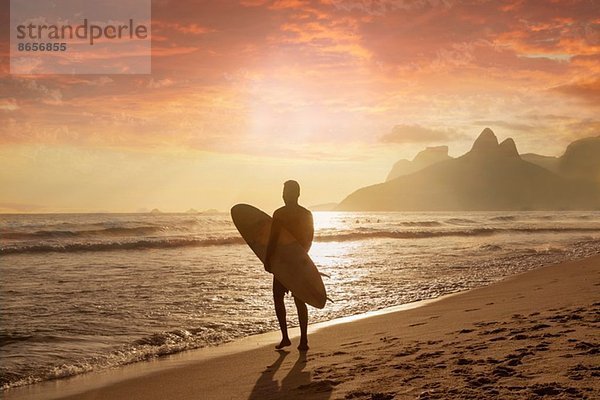 Junger Mann mit Surfbrett am Strand von Ipanema  Rio De Janeiro  Brasilien