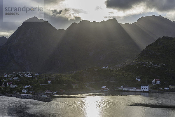 Sonnenstrahlen brechen durch die Wolken über den Bergen des Ortes Moskenes  Lofoten  Nordland  Norwegen