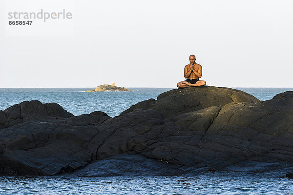 Ein Mann in Meditation  Yoga auf einem Felsen  Kudle Beach  Gokarna  Karnataka  Indien