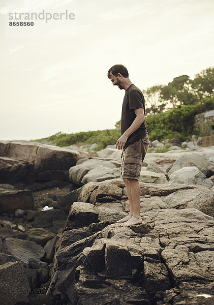 Ein Mann steht am Strand und überblickt die Felspools.