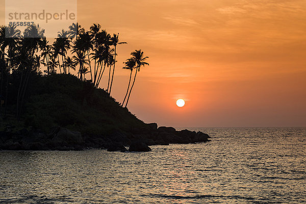 Sonnenuntergang am Strand mit Felsen und Palmen  Palolem Beach  Canacona  Goa  Indien