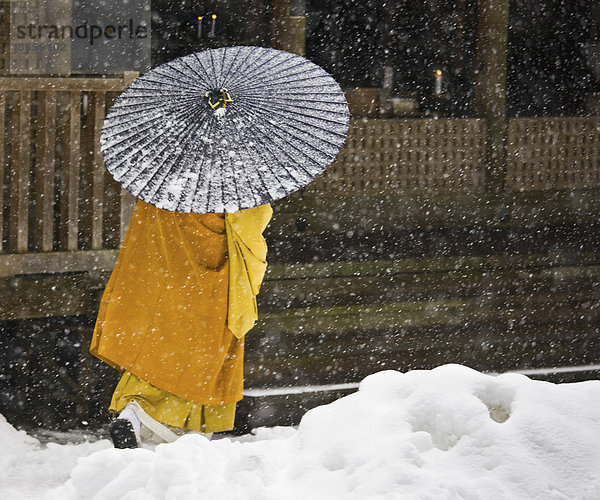Ein buddhistischer Mönch geht durch ein Schneegestöber in Koyasan  einem Zentrum des Shingon Esoterischen Buddhismus.