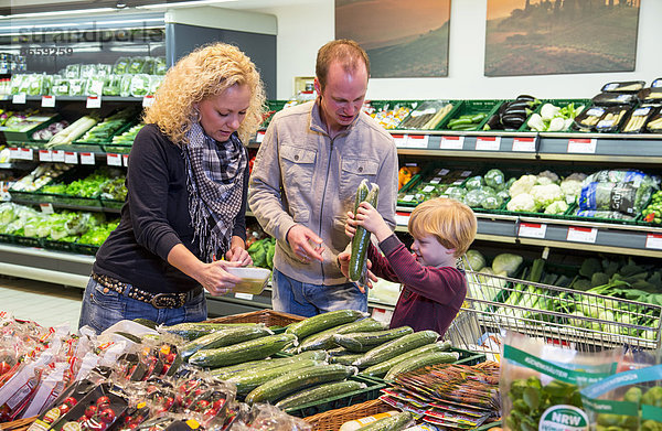 Familie mit Einkaufswagen beim Einkaufen im Supermarkt  Gemüseabteilung  Deutschland