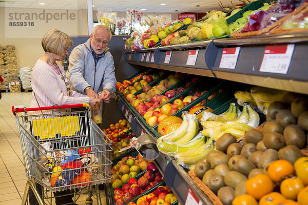 Seniorenpaar mit Einkaufswagen beim Einkaufen im Supermarkt  Obst und Gemüse  Deutschland