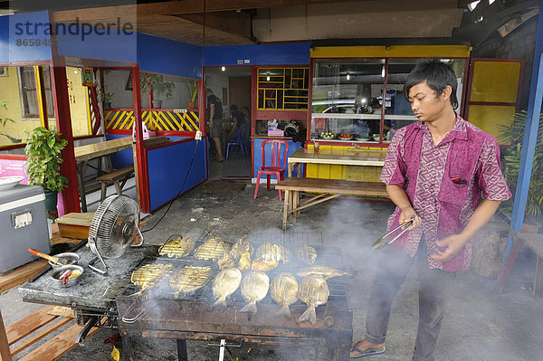 Javaner grillt Fisch in einem Restaurant  Biak Stadt  Insel Biak  West-Papua  Indonesien