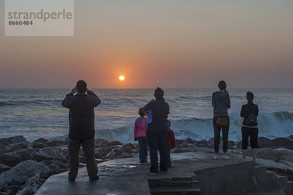 Menschen beobachten den Sonnenuntergang über dem Meer  Swakopmund  Region Erongo  Namibia