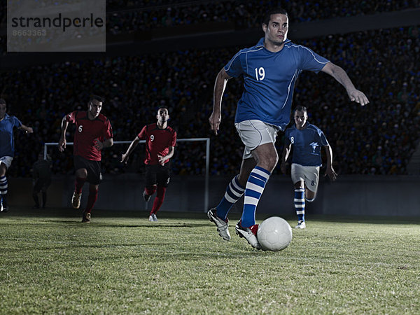 Fußballspieler jagen Ball auf Feld