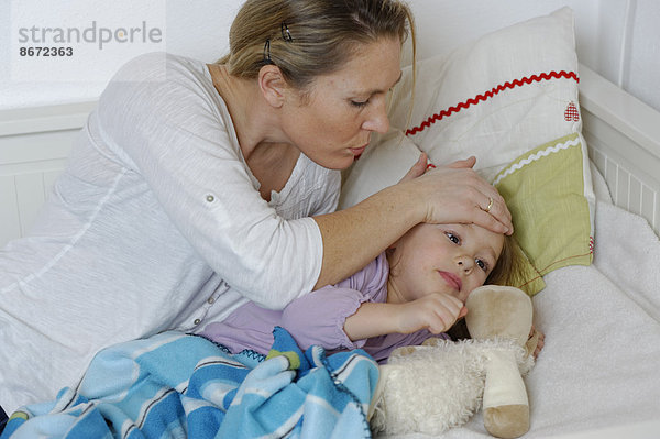 Mutter kümmert sich um ihre kranke Tochter  die im Bett liegt