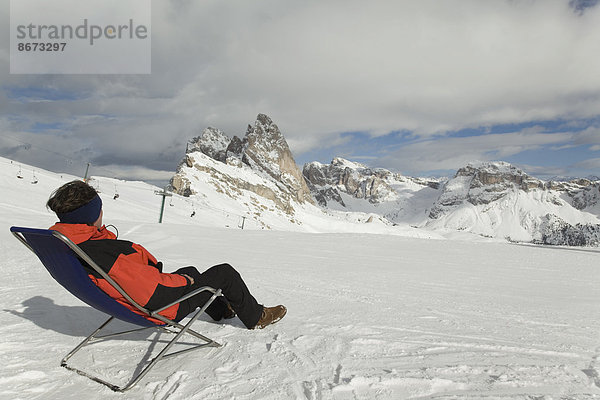 Mann sitzt am Skihang in einem Liegestuhl  Sella-Massiv  Dolomiten  Südtirol  Italien