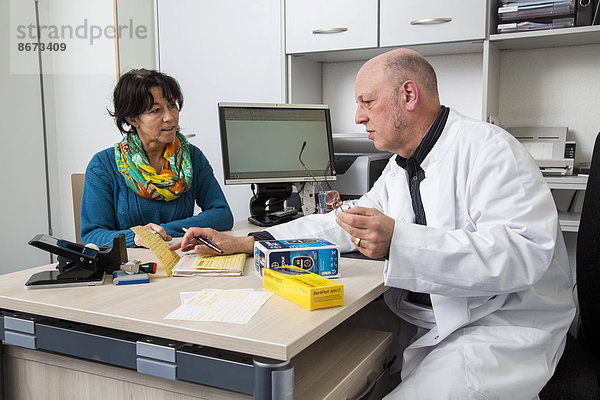 Arztpraxis  Arzt unterhält sich mit einer Diabetespatientin über den Gebrauch von Blutzucker-Messgeräten  Deutschland