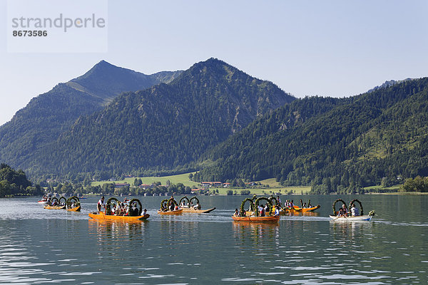 Trachtler in festlich geschmückten Plätten  Holzbooten  hinten der Brecherspitz  Alt-Schlierseer-Kirchtag  Schliersee  Oberbayern  Bayern  Deutschland