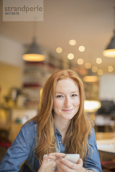 Frau benutzt Handy im Cafe