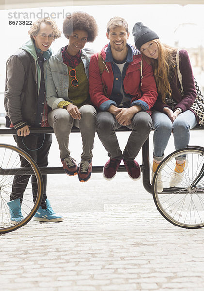 Freunde lächeln zusammen auf dem Fahrradträger.