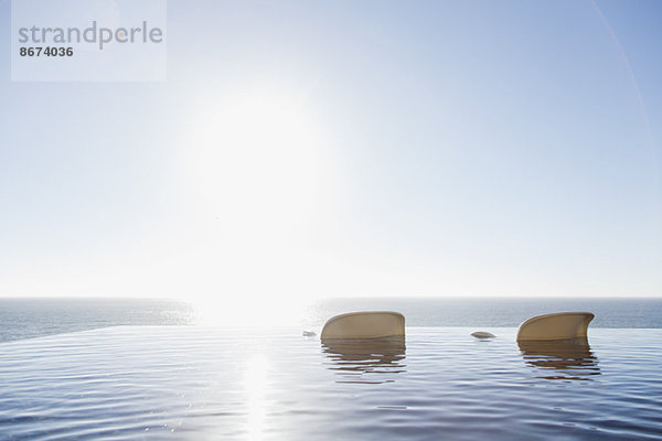 Liegestühle im Infinity-Pool mit Blick auf den Ozean