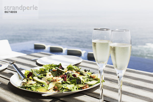 Salatteller und Champagnergläser auf dem Tisch im Freien