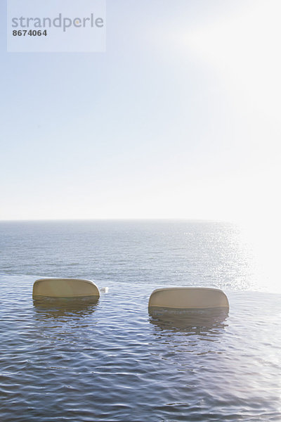 Liegestühle im Infinity-Pool mit Blick auf den Ozean