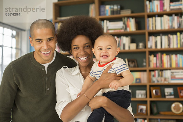 Familie lächelt zusammen im Wohnzimmer