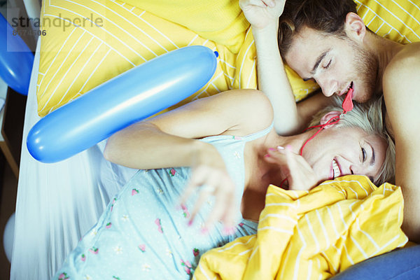 Pärchen spielen im Bett mit Luftballons