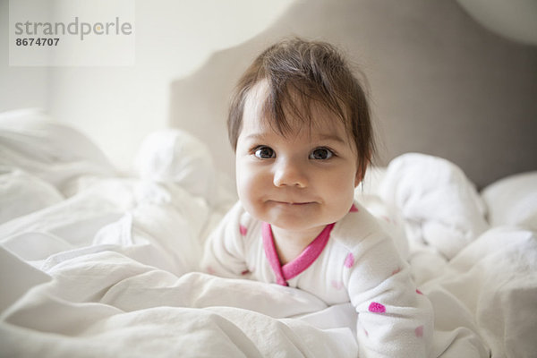 Baby Mädchen krabbelt in Bettwäsche