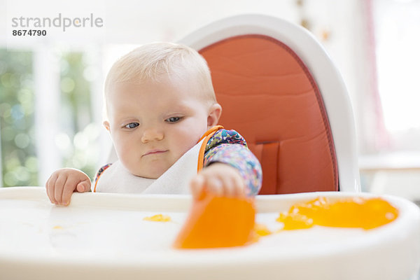 Baby Mädchen beim Essen im Hochstuhl