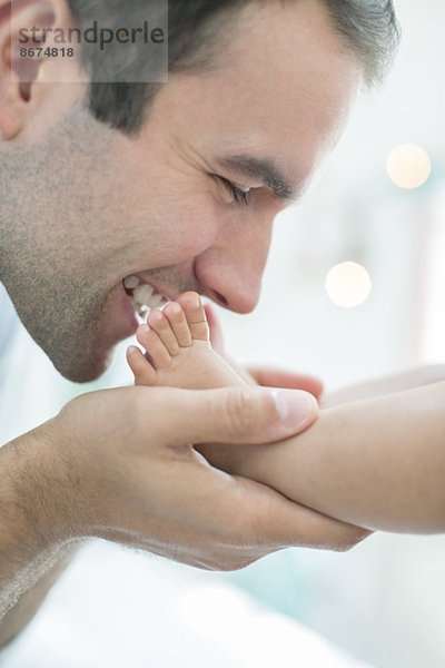 Vater küsst die Füße des kleinen Jungen